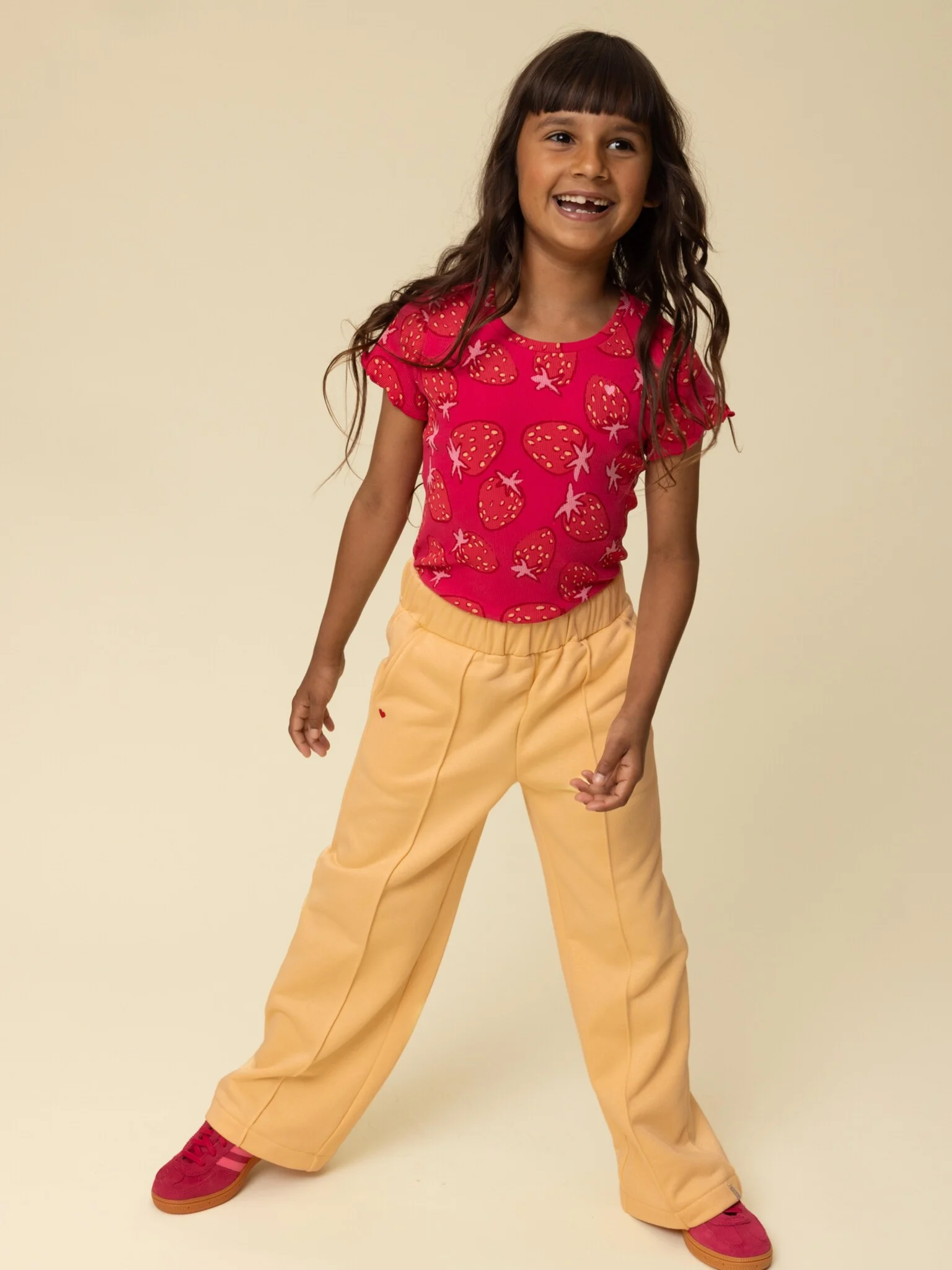 Meisje draagt abricot gele wide leg sweatbroek van Looxs Little